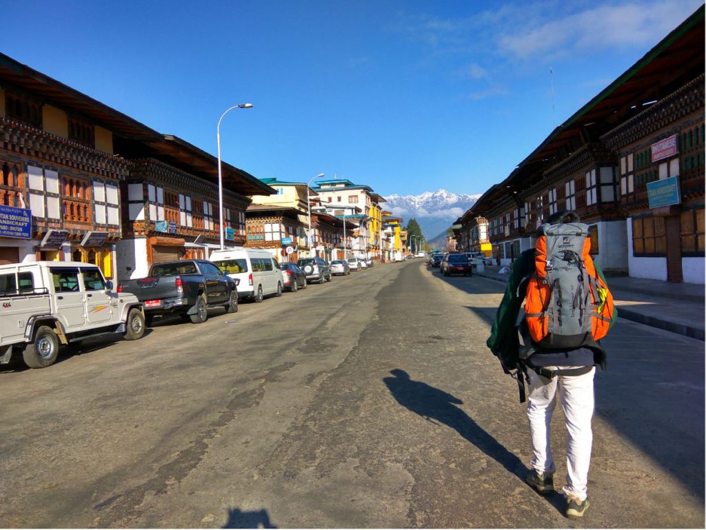 A traveler on a hilly city with an orange backpack