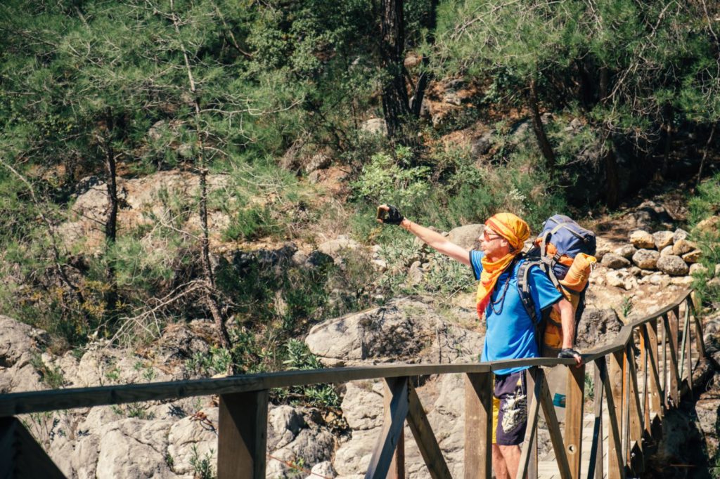 A traveller with a backpack taking a selfie with his phone