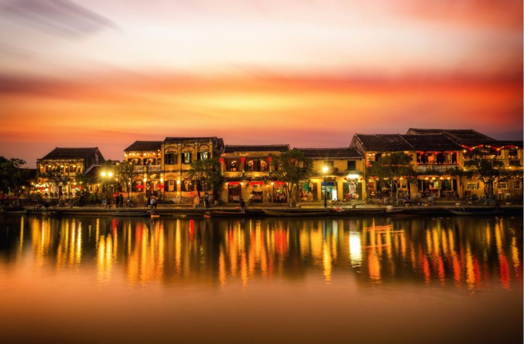 Rows of old traditional buildings next to the canal in Hoi An lit at night