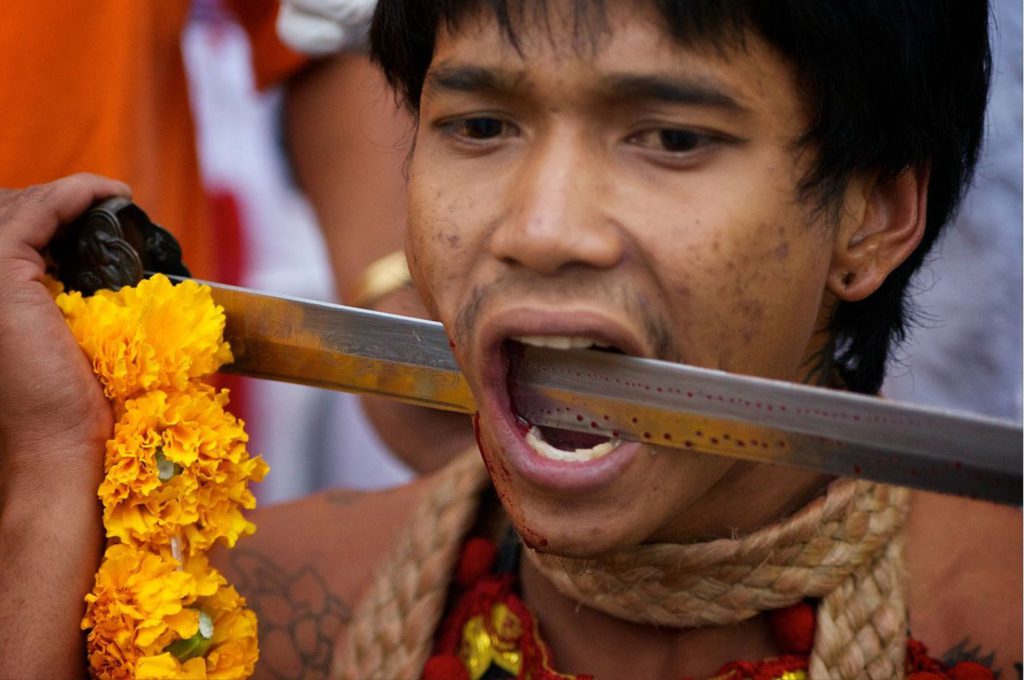 Man piercing his cheek in Phuket Vegetarian Festival
