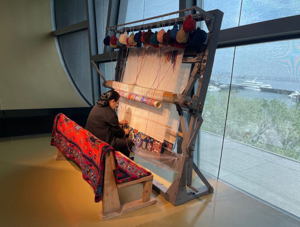 Woman weaving carpet on look inside Carpet Museum